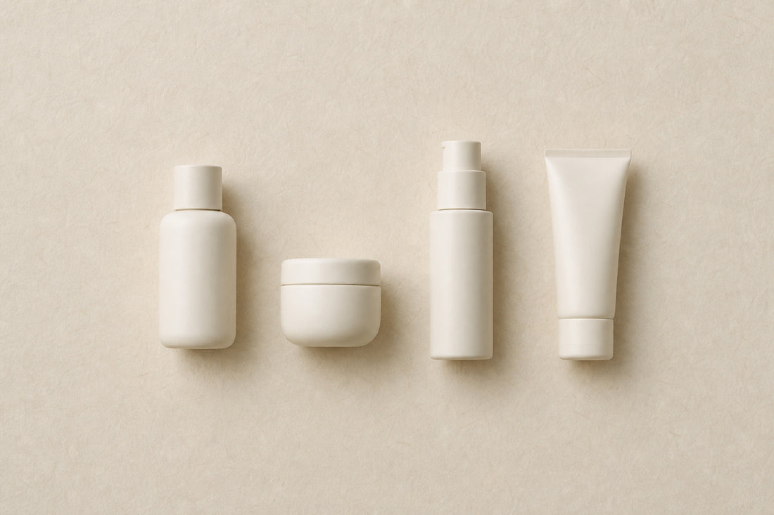 Four minimal skincare vessels in a row on washi paper