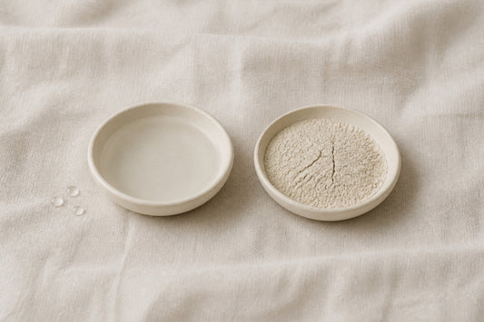 Two ceramic dishes on linen: one holding clear water, one holding dry cracked clay — dehydrated versus dry skin