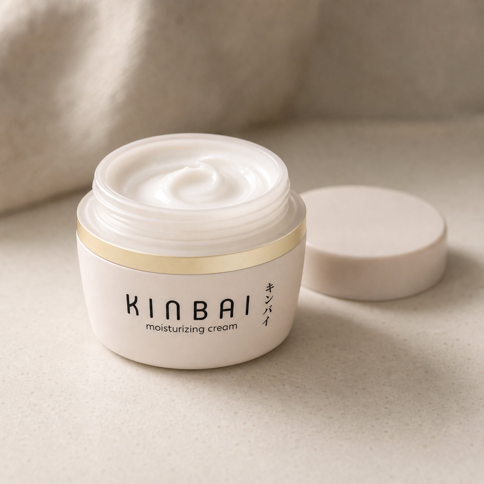Open Kinbai Moisturizing Cream jar showing the cream texture, lid beside it
